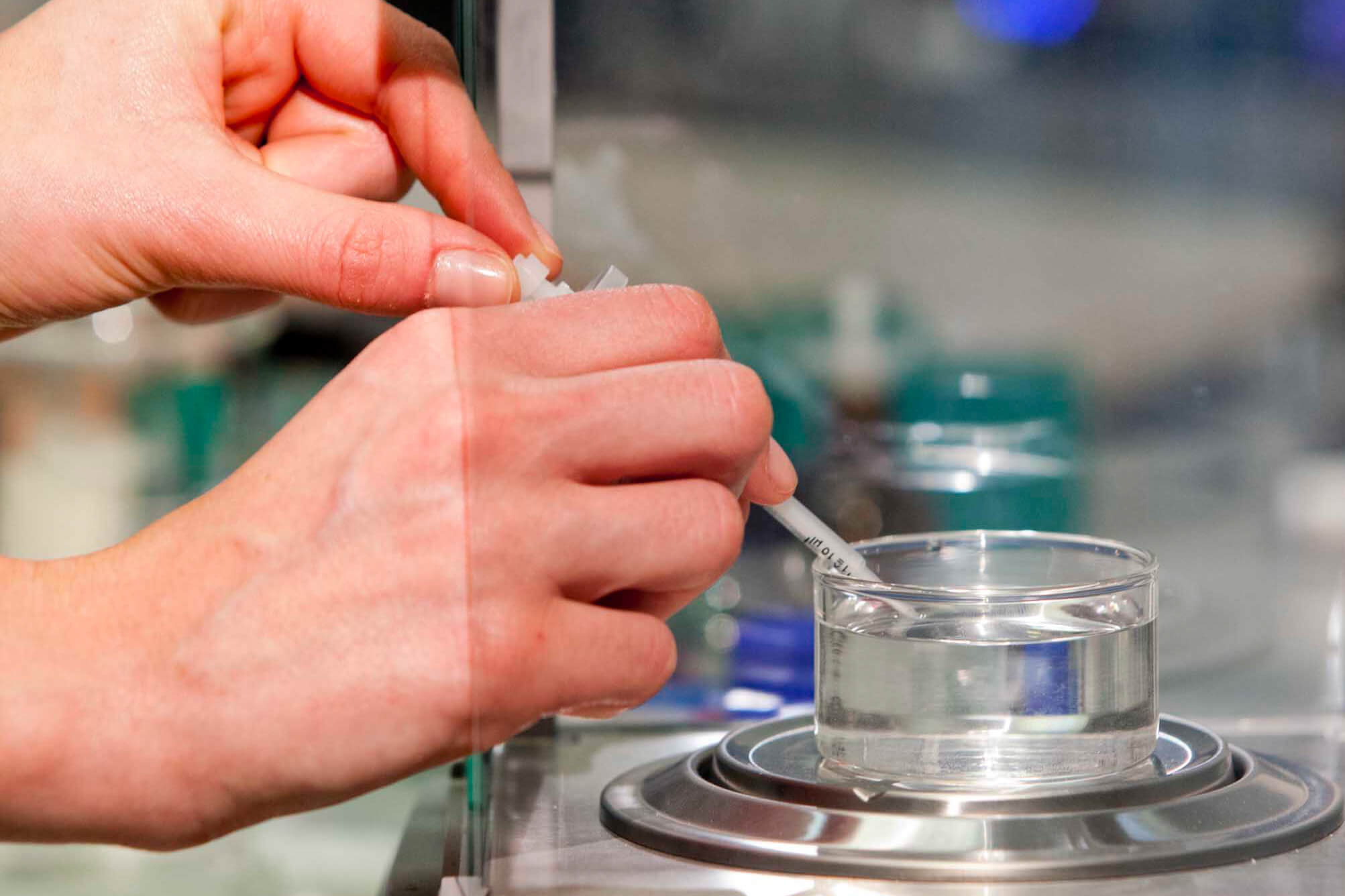 Laborprüfung von Kontaktöl auf einer Präzisionswaage mit Glasgefäß und Pipette.